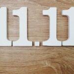 Die Zahlen 11.11 aus weißen Holzbuchstaben auf einem Holztisch.