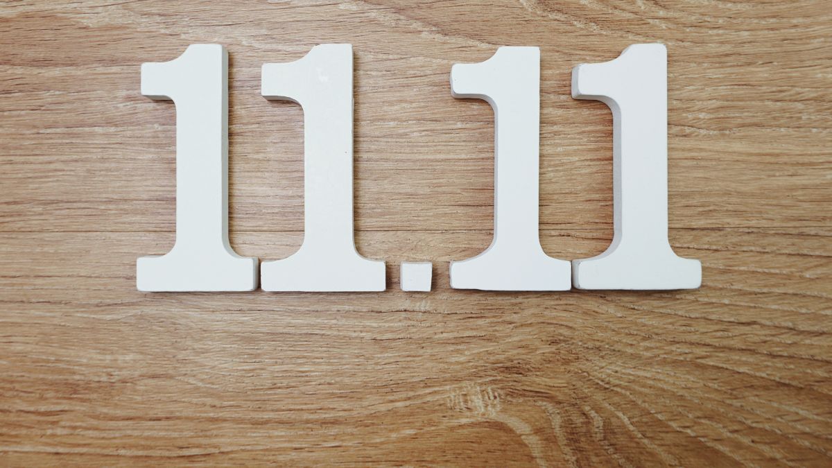 Die Zahl 11.11 aus weißen Holzbuchstaben auf einem Holztisch.