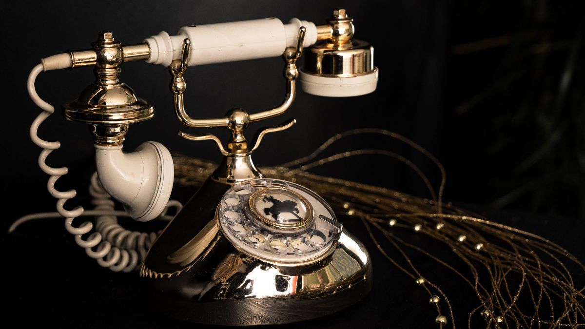Ein nostalgisches Wählscheibentelefon mit goldenen Akzenten und einer drehbaren Scheibe.
