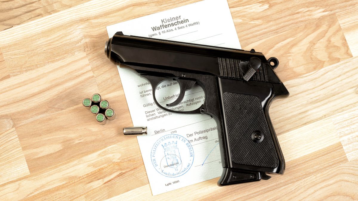 Eine Schreckschusspistole liegt auf einem Tisch neben Munition und einem Waffenschein.
