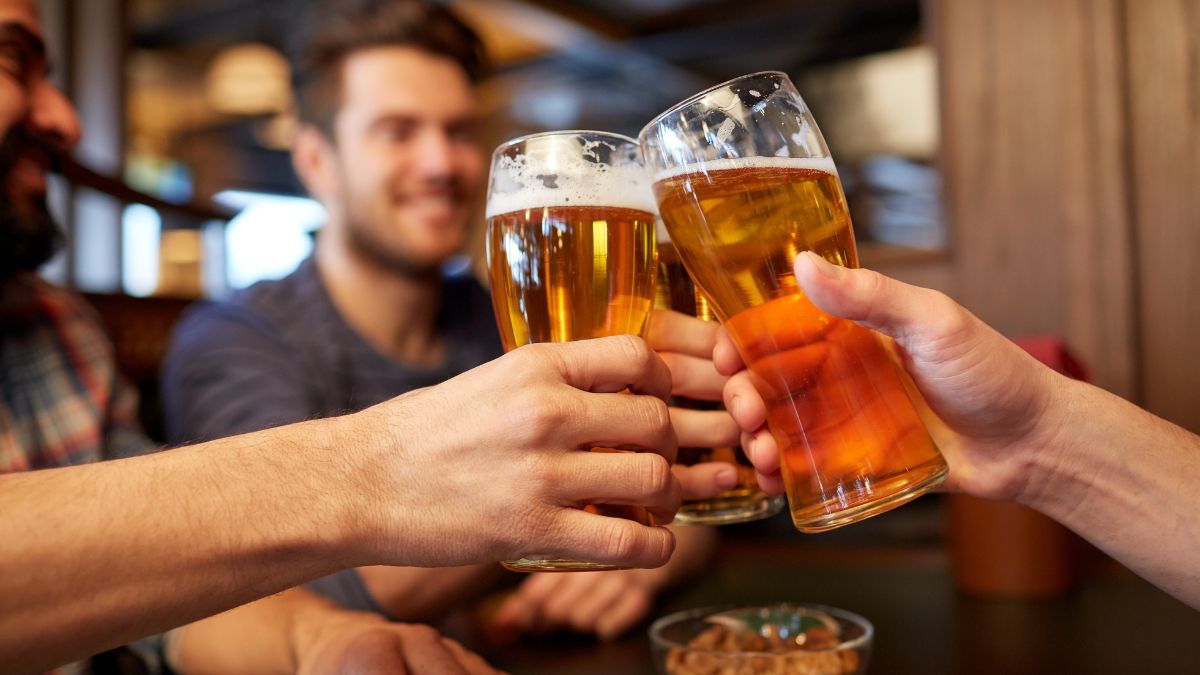 Prostata und Bier: Vorteile, Risiken und wichtige Fakten, die man kennen sollte Freunde stoßen mit Biergläsern an, während sie in einer gemütlichen Umgebung sitzen.