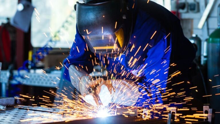 Ein Schweißer arbeitet präzise mit einem Impulsschweißgerät, Funken sprühen.