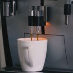 Eine Tasse frischer Kaffee wird aus einem Kaffeevollautomaten ausgegeben.