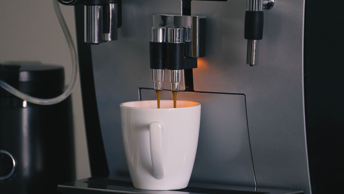 Eine Tasse frischer Kaffee wird aus einem Kaffeevollautomaten ausgegeben.