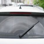 Ein Heckscheibenwischer auf einer nassen Autoscheibe, die Sicht ist eingeschränkt.