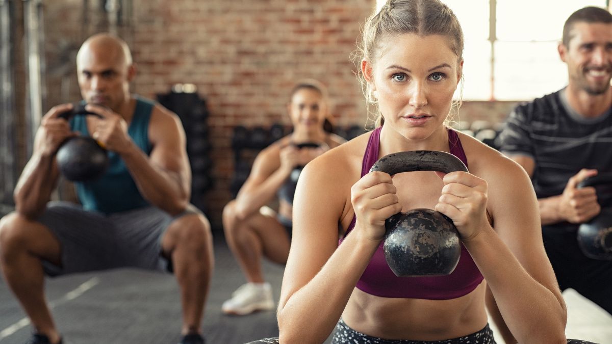 Eine Gruppe von Menschen trainiert mit Kettlebells in einem Fitnessstudio.