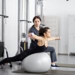 Eine Frau führt eine Kinesiologie-Übung auf einem Gymnastikball aus.