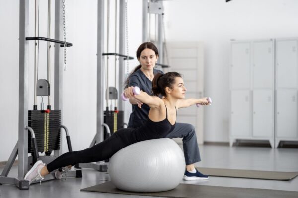 Eine Frau führt eine Kinesiologie-Übung auf einem Gymnastikball aus.