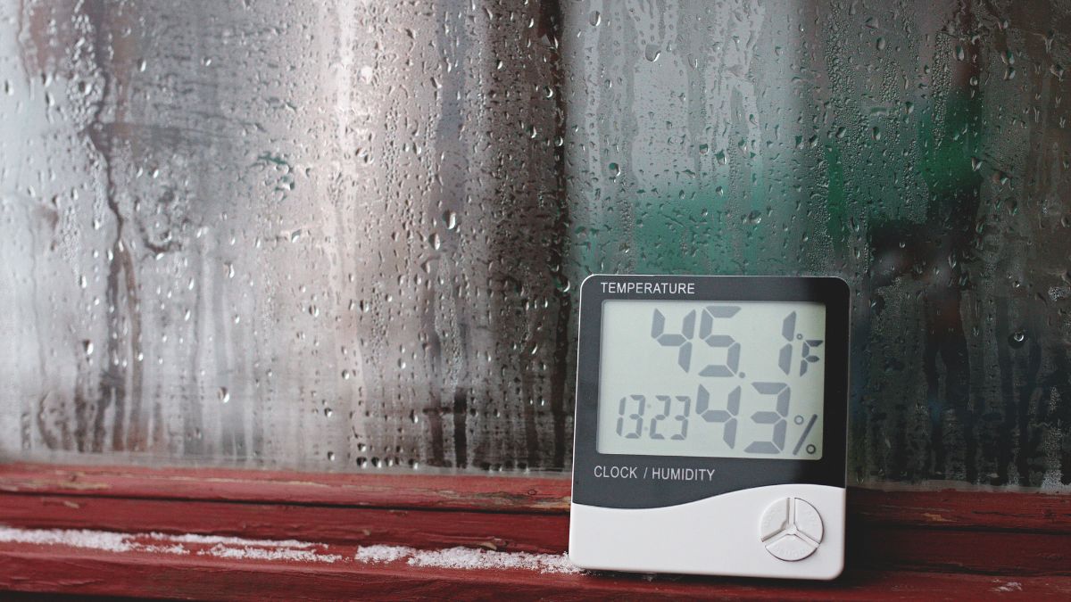 Ein Thermometer zeigt 45,1°F und 43% Luftfeuchtigkeit an, während Wassertröpfchen an einem Fenster sichtbar sind.