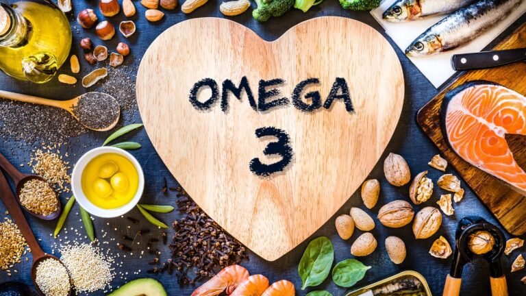 Eine Holzplatte in Herzform mit der Aufschrift Omega 3, umgeben von gesunden Lebensmitteln.