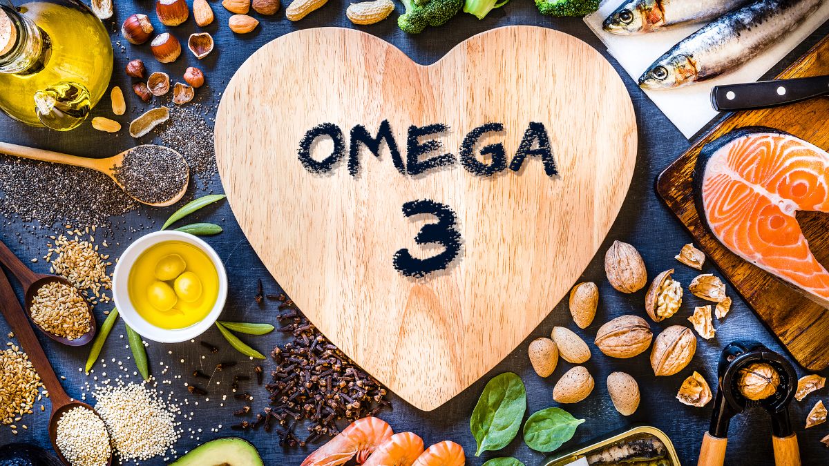 Eine Holzplatte in Herzform mit der Aufschrift Omega 3, umgeben von gesunden Lebensmitteln.