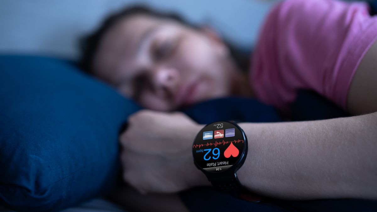 Eine schlafende Person mit einer Smartwatch, die den Puls anzeigt.