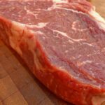 Frisches Rindersteak auf einem Holzbrett, bereit zum Kochen.