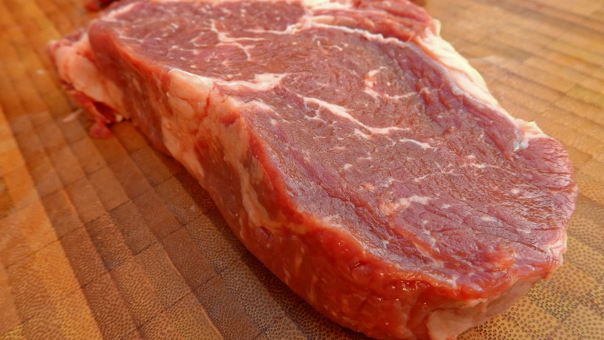 Frisches Rindersteak auf einem Holzbrett, bereit zum Kochen.