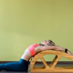 Eine Frau dehnt ihren Rücken auf einer Streckbank in einem hellen Raum.