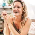 Eine lächelnde Frau über 40 sitzt entspannt im Freien und genießt den Moment.