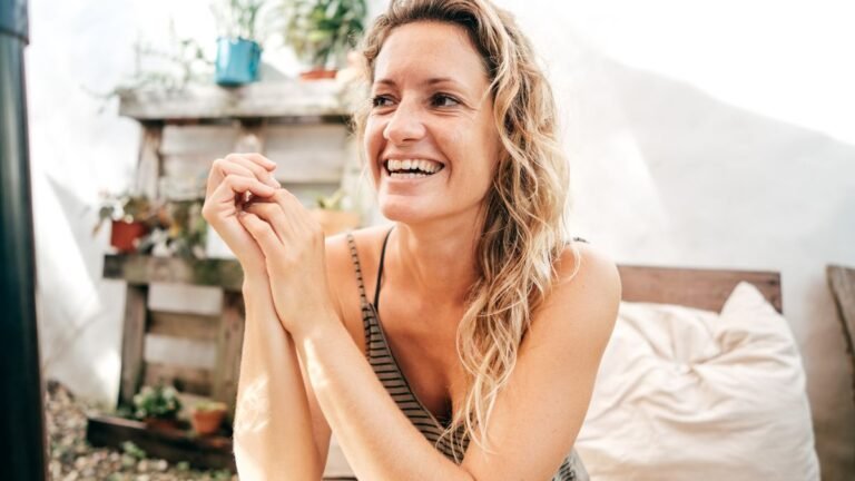 Eine lächelnde Frau über 40 sitzt entspannt im Freien und genießt den Moment.