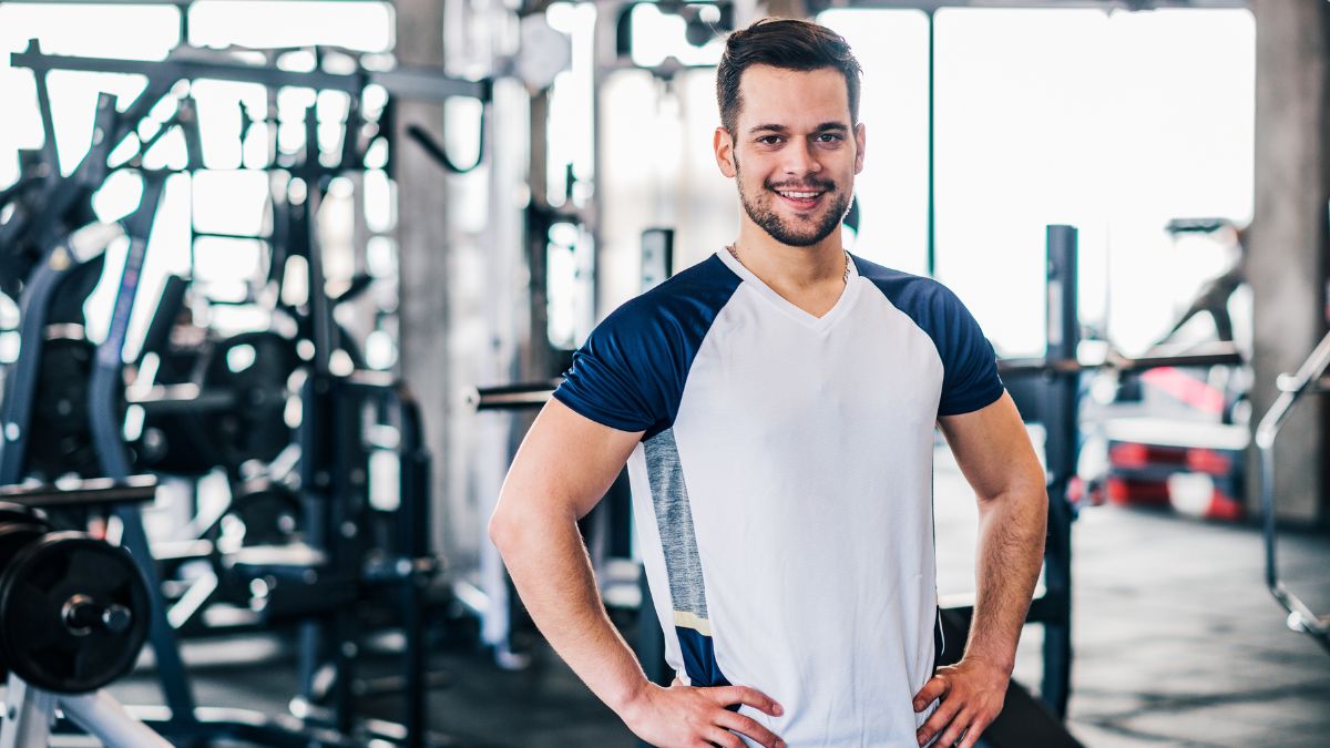 Ein sportlicher Mann in einem Fitnessstudio, der lächelt und Selbstbewusstsein ausstrahlt.