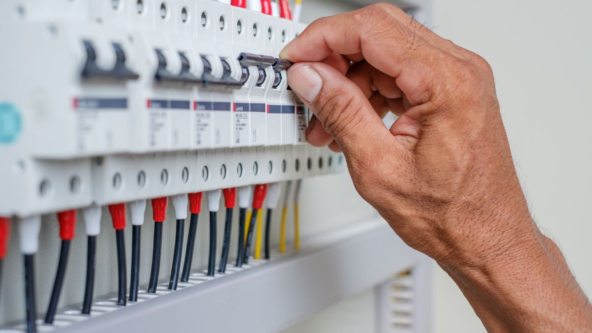 Sicherungsschalter: Wie er arbeitet und dein Stromnetz schützt Eine Hand schaltet einen Sicherungsschalter in einem Stromverteilerkasten um.
